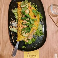 A crispy crepe flavored with turmeric, made with rice flour, bean sprouts, sautéed tofu, accompanied by salad, cucumber, fresh mint, carrot, vegan nem sauce, and toasted peanuts. at Harmonie Bowl & Juice in Strasbourg