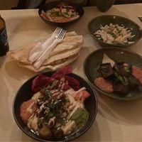 Hummus plate and eggplant salad beside Israeli beer  at Akko Hummus Bar in Leipzig