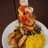 Tofu Hanging Kebabs! Devons Dragonfly Farm marinated Tofu kebabs served skewered with cherry tomatoes, peppers, onions above rice, homemade wedges & salad garnish at Rock Garden in Torquay