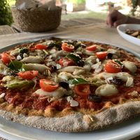 Pizza with a dough from wholemeal flour, vegan mozzarella, tomatoes, marinated basil, almonds, zucchini & olives  at Ecosteria Parco Santi Angeli in Santi Angeli