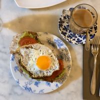 Oat milk coffee with egg, tomato and avocado sourdough toast. at Blu Cafe in Santiago De Compostela