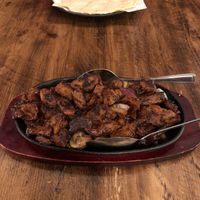 Vegan beef sizzler with garlic cheese bread in background.  at Mr Singh's in Wolverhampton