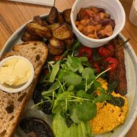 Vegan breakfast: potatoes, sourdough and vegan spread, fried mushrooms and tomatoes, tempeh, avocado, tofu scramble, avocado and house beans, topped with salad leaves at Partisan in York