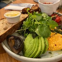 Vegan breakfast: potatoes, sourdough and vegan spread, fried mushrooms and tomatoes, tempeh, avocado, tofu scramble, avocado and house beans, topped with salad leaves at Partisan in York
