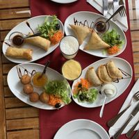 Starters: spring rolls, cheese balls, samosas and seitan starter with maracuya and pineapple lassis  at Os Tibetanos in Lisbon