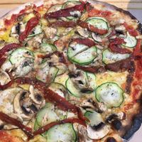 Veggie pizza with lots of vegan cheese underneath the veggies at Pizza Basta Restaurante in Cambrils