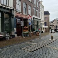 Outside seating area, window with cakes and entrance at Bairro Alto in Nijmegen