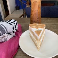 🌏⚖️🇵🇸🤰🏽 Massive Slice of 🕌⚖️ Coconut Caramel Cake 🇵🇸🗝️🌎👩🏽‍🍼, with a tall glass of Coffee🇵🇸🕌🇹🇭🕌🇵🇸 Latte (w at Alchemy Vegan in Chiang Mai