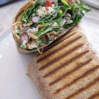 Early riser breakfast wrap. The whole wheat tortilla was filled with quinoa, black beans, corn, pulled portobello mushrooms, spinach, caramelized onions, red pepper, tomato, bragg seasoning, mayo, and again delicious cashew cheese. at Fruitive - Colley Ave in Norfolk