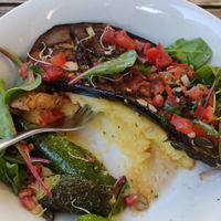 Creamy polenta with roasted eggplant, tomato and dark olives sauce, chiogga beet, and pomegranate seeds. at SOJI in Marseille