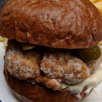 White residue on "Nashville hot 'chicken' burger patty, with a thin thread underneath at The Blacksmith & The Toffeemaker in London