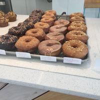 Doughtnut selection (1/16/18). Left to right: chocolate sprinkles, toasted coconut, earl grey and peanut butter. Vegan labeling and prices. at The Sweet Praxis in Syracuse