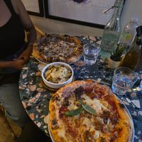 Parmigiana party nearside and I think black truffle pizza on far side my wife ordered. Garlic potatoes in the middle. at Purezza Camden in London