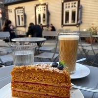 “No-honey” cake, a cafe latte, and outdoor seating. at Mazā Terapija in Riga