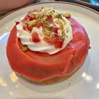Strawberry fields donut (Strawberry glaze, pistachio praline and whipped cream topped with fresh strawberries & almond streusel)  at L'Artisane Creative Bakery in Coral Gables