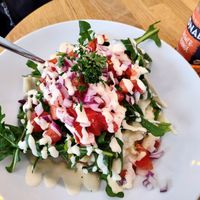 Monthly special for June - white asparagus with "cream" sauce, tomato cucumber arugula salad. Giant baked potato underneath. at Erdapfel in Hamburg