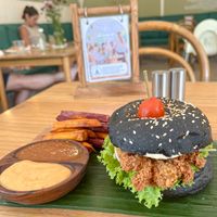 Fried Chickenless Burger – crispy battered oyster mushrooms on a charcoal bun with slaw and vegan mayo, served with baked sweet potato fries tomato sauce, and sambal mayo at Dharma Coffee & Juice in Ubud