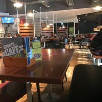 Seating near the windows, all with views of TVs and children’s play area at Sports Cafe - Center Parcs in Brandon