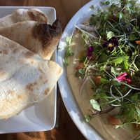 Hummus and flat bread aka delicious soft pizza and a bad ass plate of hummus topped with greenery and florals - it’s ‘uge!! at Due South in Albany