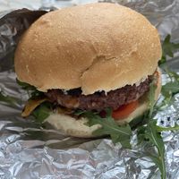 Vegan burger "Brezmesni kralj" with potato bombette, soy patty, barbecue sauce, fried onion, arugula, tomato, vegan cheddar cheese.  at Bullizza in Ljubljana