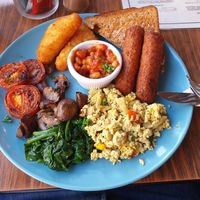 "Planted Swamp" vegan breakfast. Has veggie sausages, hash browns, grilled tomatoes, mushrooms, beans, toast, wilted peppered spinach and a tofu scramble with peppers at Cranberry Swamp in Whitby