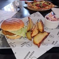 Spicy bean burger with wedges & coleslaw. Top of photo is a personalised pizza at Prana Cafe in Leicester