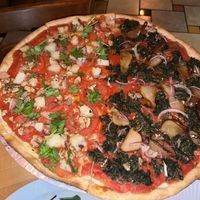 Half and half vegan pizza. Carmelized peaches, spinach, mushrooms,onions and garlic. Also potatoe,tomatoes,garlic, walnuts and cilantro    at Zia Gourmet Pizza in San Diego