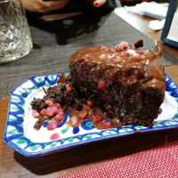 Brownie con chocolate derretido y granada por encima at El Piano in Granada