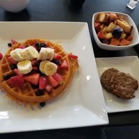 Vegan waffle with blueberries, strawberries, and bananas. Plant based sausage and home fries at Waffles INCaffeinated in Beaver