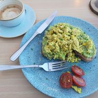 Scrambled tofu, smashed avo on dark rye with a few tomatoes, washed down with a flat white w. oat milk! at Roots Cafe in Abergele