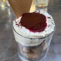 Cremoso de chocolate blanco y coco con base de galletas, helado de avellana y salsa de frutos rojos  at Vegania in Madrid