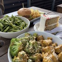 The broccoli tofu and peanut sauce bowl, edamame, burger and kettle chips, and a slice of cake  at The Bye and Bye in Portland