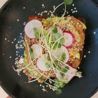 Avocado toast on sourdough toast with tomato chutney, hemp hearts, radish, and salad. at Naive in Louisville
