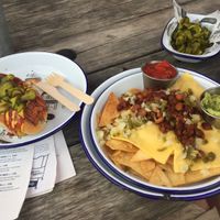 Vegan NOT dog (with a couple bites missing on the ends and added pickle) and loaded house-made nachos with vegan chilli, onion, jalapeños, salsa and guac! at Hubbox in St Austell