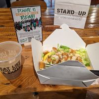 mocha shake and Crispy Chikin Caesar salad in disposable containers in front of sign promoting environmentalism at Stand-Up Burgers in Berkeley