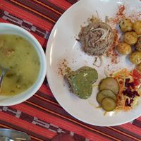 Corn soup, and main plate with rice, potatoes, salad, and mixed grains with pesto sauce on top at Alma Natura in Medellin