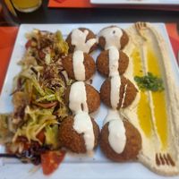 Falafel with hummus and salad, garnished with tahini sauce at Middle East in Como