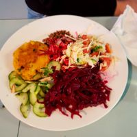 Vegi-burger main dish with salads: cucumbers, fermented (pickled) red cabbage, garden vegetables and toasted sunflower seeds with soy sauce. at The Grove Veggie Kitchen in Limerick