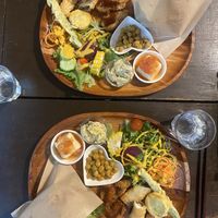 Assiette burger vegan, servie avec un assortiment d’entrées, ici salades, pois chiches, tempura de légumes, tofu frit, et tofu soyeux épicé.  at Ramuna in Nara