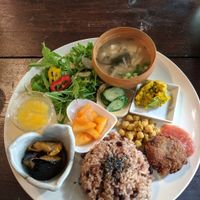 Brown rice with fermented vegetables and pickles, chickpeas, marinated tomatoes, lemon jelly, pumpkin, salad, miso soup and onion croquette. at Ramuna in Nara