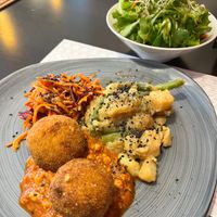 Arancini in tempeh ragu sauce, potatoes and green beans glazed with soy sauce, oriental carrot and purple cabbage salad main dish and mixed salad in the back. Daily menu, 20.04.26. at Vegehop in Zagreb