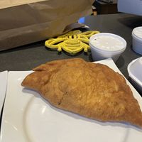 Panzerotti takeout. Hard to see size but it’s just about smaller but close to football sized.   at Amico's Pizza in Toronto