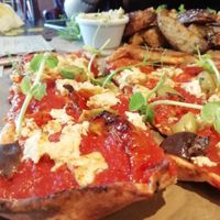 Vegan flatbread pizza with crumbled miso tofu, sunblush tomatoes, olives, and pea shoots at The Font in Chorlton