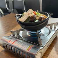A dumpling and mushroom hot pot. A large cooking pot; filled to the brim. Is placed on a portable gas burner. The burner is lit, and when the broth boils, the hot pot is ready!  at K-pub in Adelaide