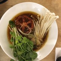 Mushroom based broth, topped with enoki and braised tomato at Vegan Ramen Shop - Mokotów in Warsaw