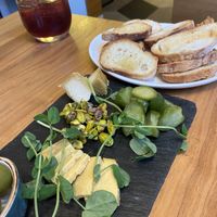 Cheese platter with dill pickles green olives, and roasted pistachios  at Althea in Chicago