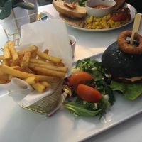 The cheeseburger with charcoal bun, onion rings and fries.  at Naked Bakery in Edinburgh