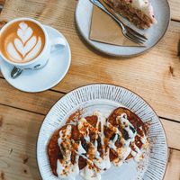 Oat milk cappuccino, raspberry & lemon cake, oat & banana pancakes  at Jaunty Goat Coffee - Northgate St in Chester