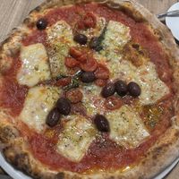 Marinara pizza topped with tomato sauce, cherry tomatoes, basil, taggiasche olives, garlic, oregano, and vegan mozzarella  at Simbiosi in Florence