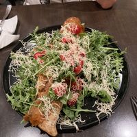 baguette shaped crust filled with ricotta and mozza, speck ham on top, sprinkled with parmesan - with salad and tomatoes  at Utopia in Nice